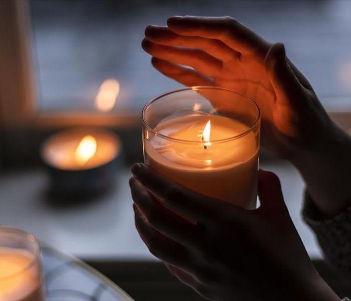hands holding candle with candles in background